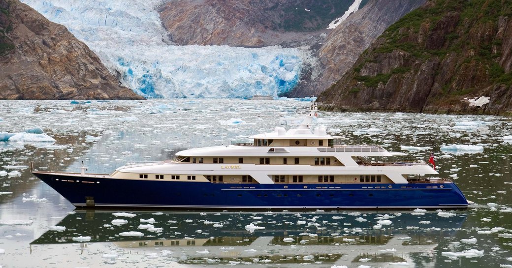 superyacht with blue hull at base of glacier