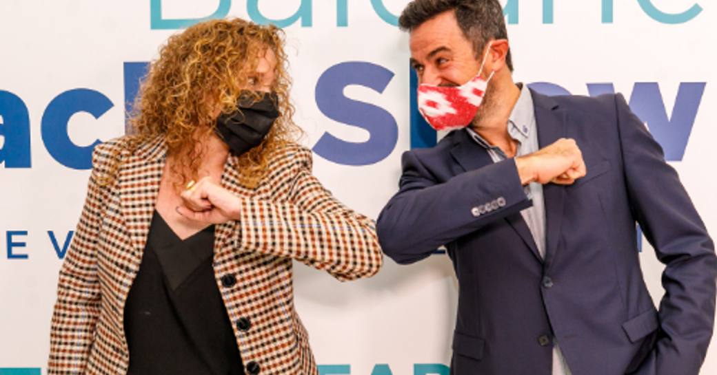 Two masked representatives from Palma Superyacht Show and Balearic Yacht Show touching elbows.