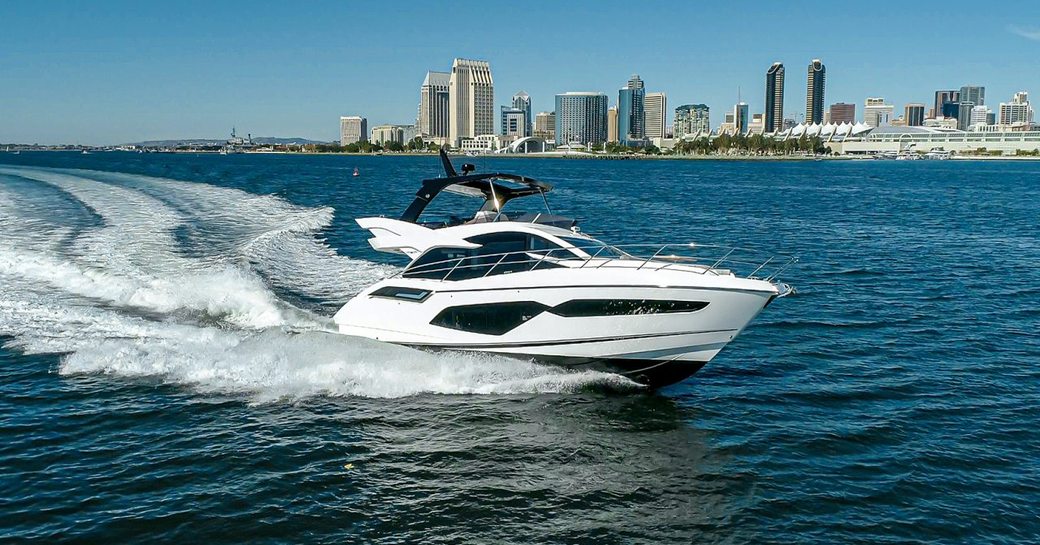 Side view of Sunseeker Manhattan 55 underway, cosmopolitan skyscrapers in far background.