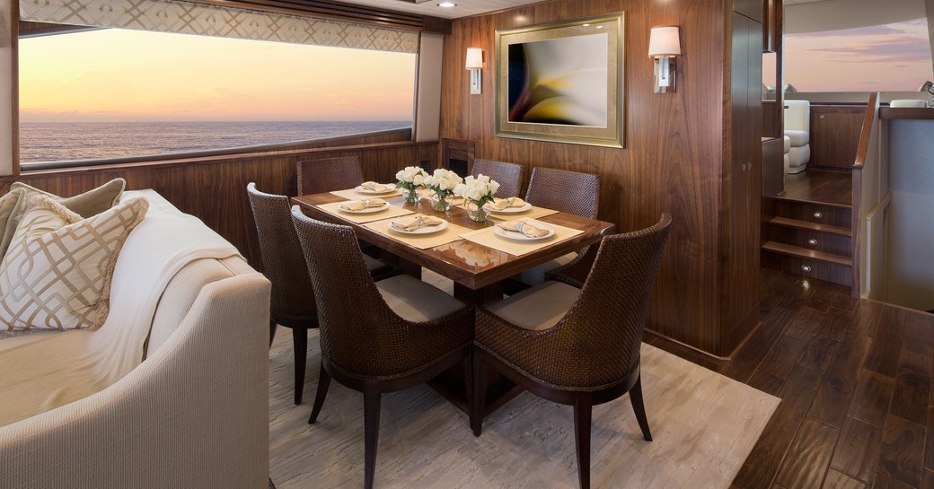 Dining area on the main deck onboard Viking 75 MY, dark wood dining table surrounded by chairs, overlooking wide window.