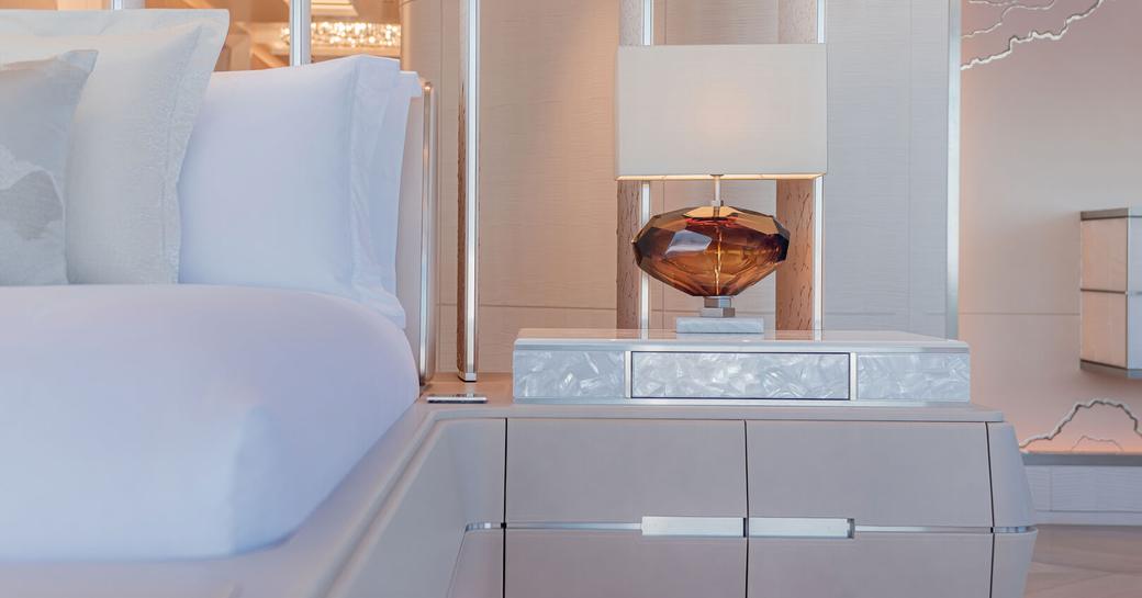 Close image of a bedside table and lamp in a guest cabin onboard superyacht H3