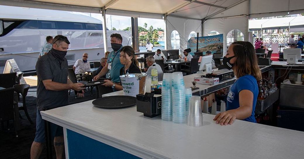 Catering tent at FLIBS with bar and small tables, servers wearing masks and abiding by social distancing