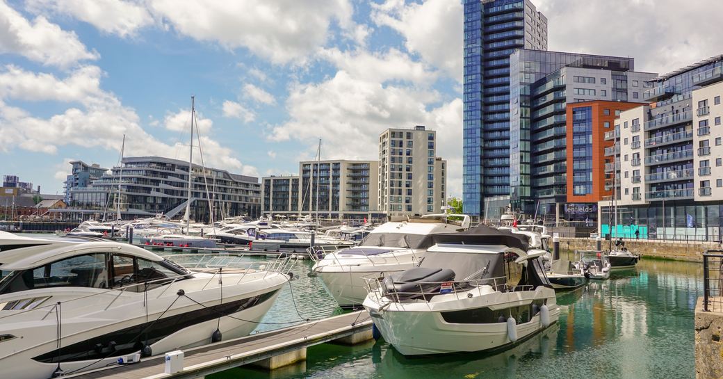 Ocean Village Marina in Southampton, motor boats moored along jetties, hotels and infrastructure in background.