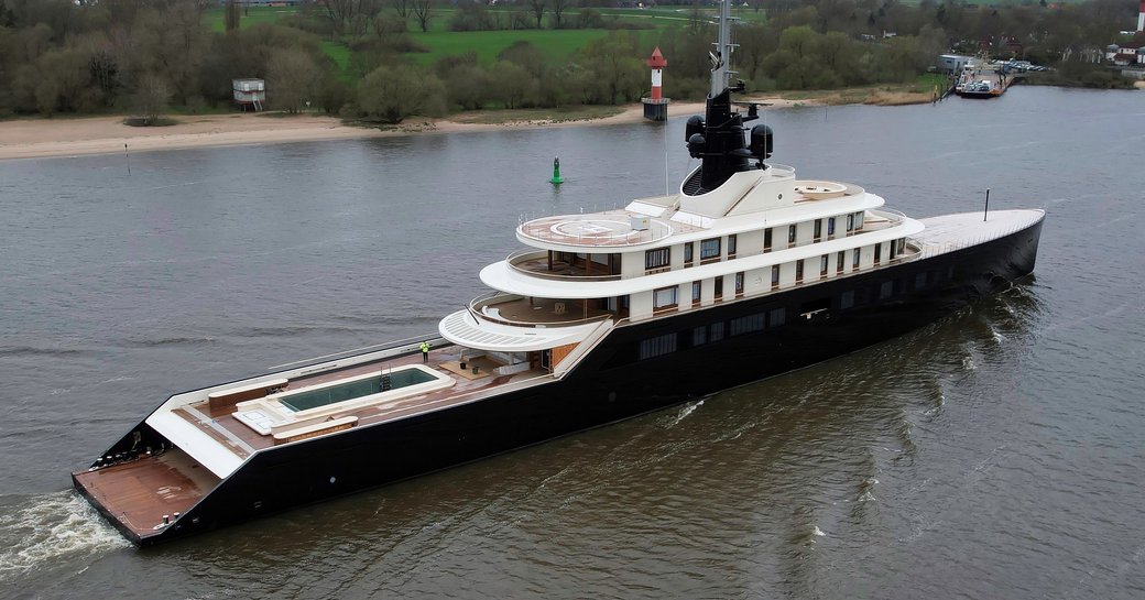 Aft view of M/Y LIVA underway along a river in Germany, with green countryside on far side of river.