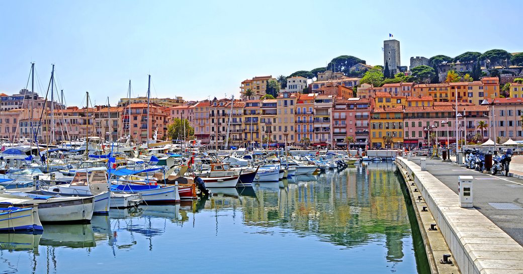 Sailing boats berthed in Cannes marina. Old town visible in the background.