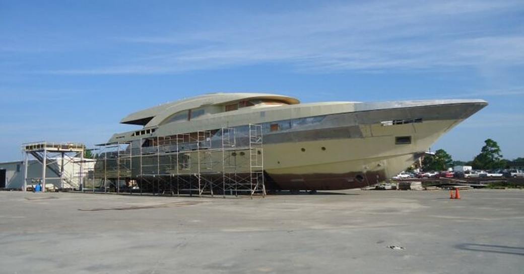 Side view of the bow of incomplete Trinity T056 hull on tarmac, surrounded by scaffolding.