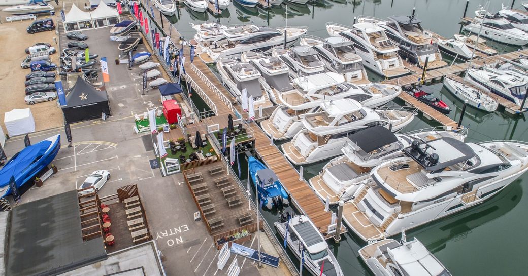 Elevated view of Swanwick marina setting up for British Motor Yacht Show. Multiple motor yachts berthed alongside dock.