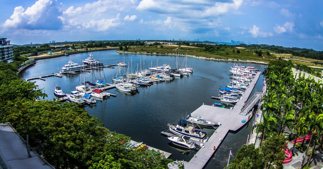 Overview of Puteri Harbour, Malaysia. Multiple boats berthed, surrounded by green foliage.