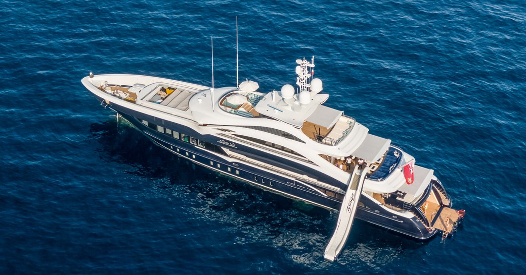 Aerial view of M/Y JULIA at sea, with water slide leading down into the sea.