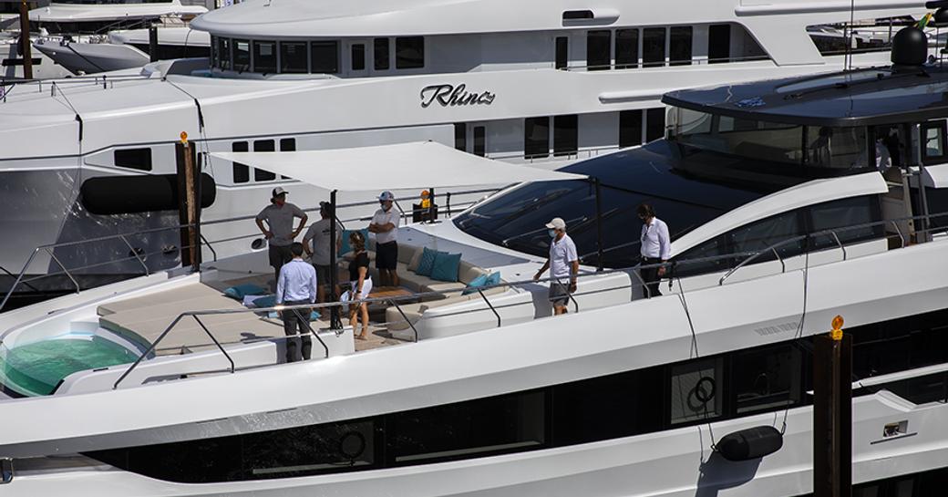 Row of Superyachts moored at FLIBS, visitors viewing upper deck exteriors