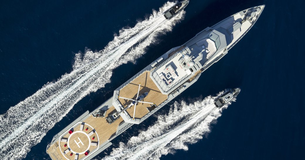 Bird's eye view of superyacht BOLD. Tenders speeding along either side, surrounded by sea.