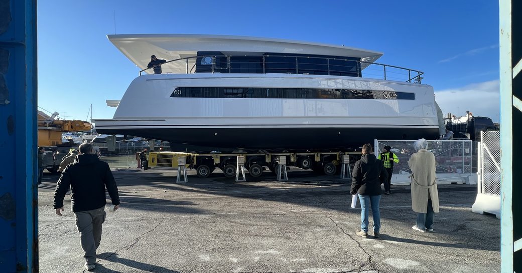 Silent 60 hull on launch day, sat on transporter on tarmac, surrounded by construction crew.