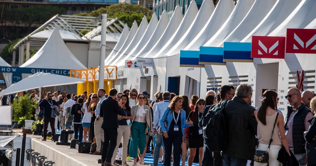 Visitors to the Monaco Yacht Show exploring exhibitor stands along dockside,