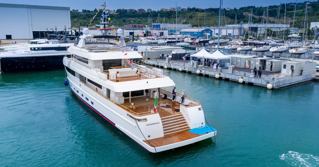 Crowbridge explorer yacht by Cantiere delle Marche in harbour, with a number of other boats docked to the right hand side and hills in the background