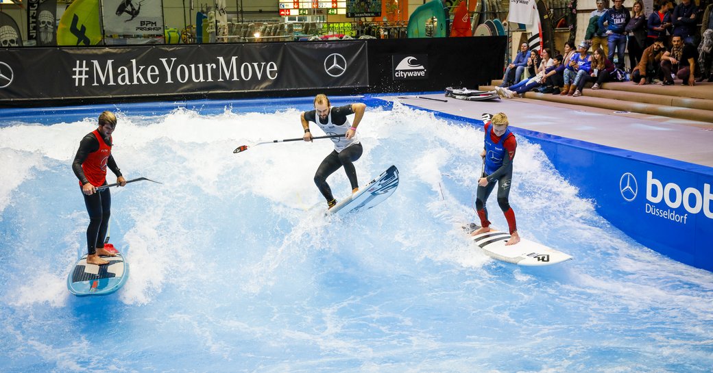 Watersports demonstration at Boot Dusseldorf, three surfers on wave fully kitted out.