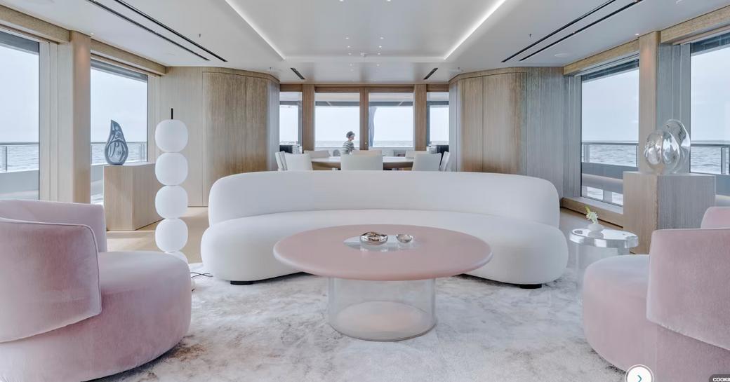 Overview of a lounge area onboard superyacht ENTOURAGE, withcurved sofa and crushed velvet armchairs facing in to a round coffee table.