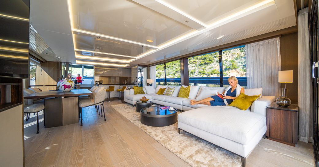 Large salon on Sunseeker 90 Ocean with lady reading book on sofa