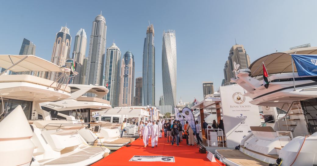 Men walking past yacht on docks with skyscrapers visible in background