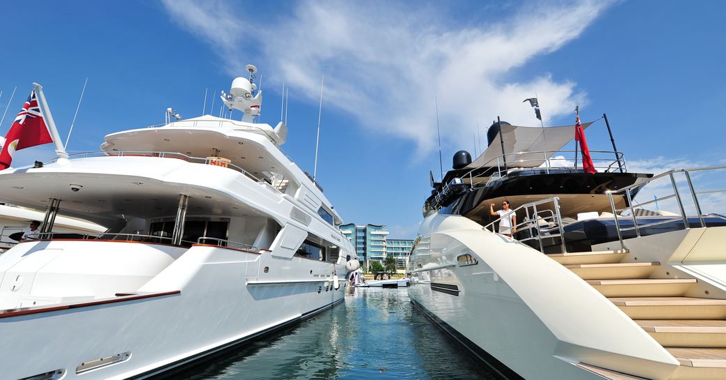 Aft view of two superyachts at anchor in marina