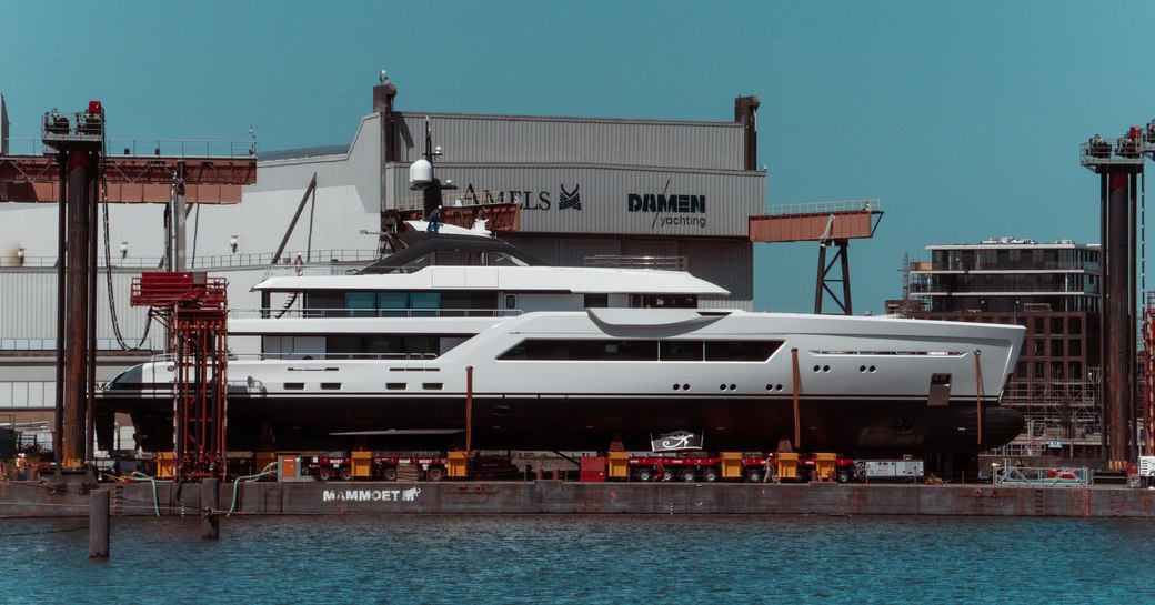 Side view of Amels 60 on the dockside outside the Damen Yachting facility in the Netherlands.