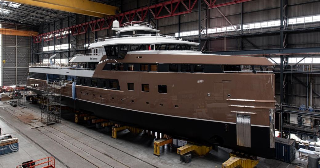 Damen Yachting's 'La Datcha' Explorer Yacht in warehouse with distinctive chestnut color hull