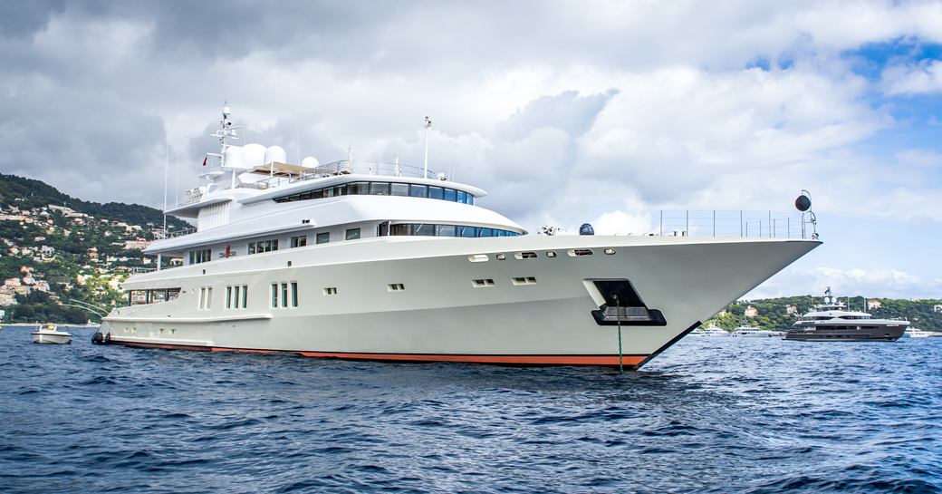 Superyacht Coral Ocean underway, surrounded by sea with land in distance port side.