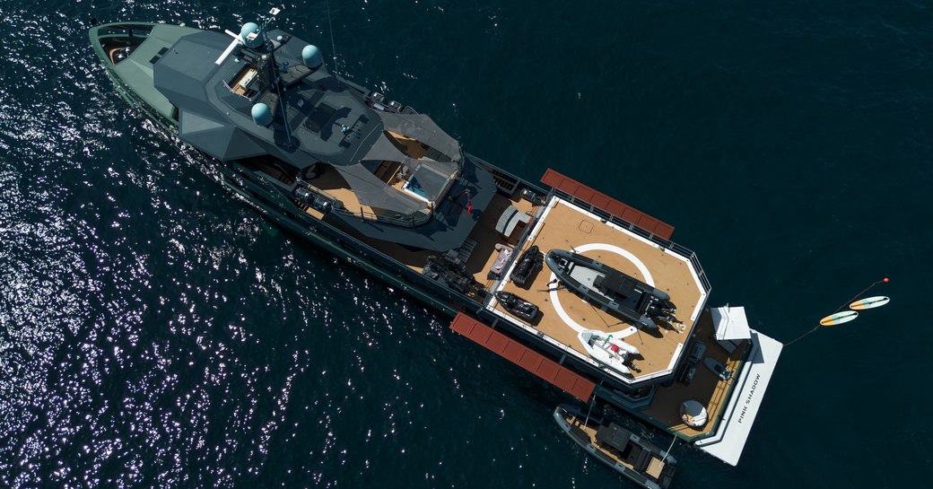 Damen Xplorer yacht PINK SHADOW shown in aerial shot over port quarter deck, side profile and above, the yacht is stationry as the yacht tenders are by the port side and watercraft are in the water off the starboard quarter, big RIB shown on the helipad, with small rib on it's port side