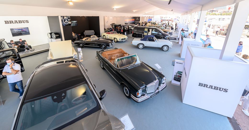 Luxury cars on display at Monaco Yacht Show inside exhibition area.