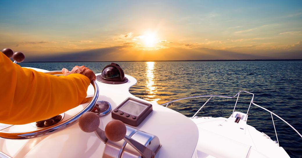 Hand of captain on steering wheel of motor boat in the blue ocean 