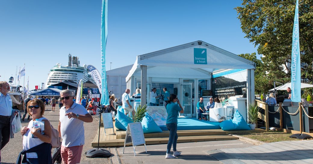 Exhibitors tent at Southampton Boat Show with cruise ship berthed in background and visitors walking towards photographer.