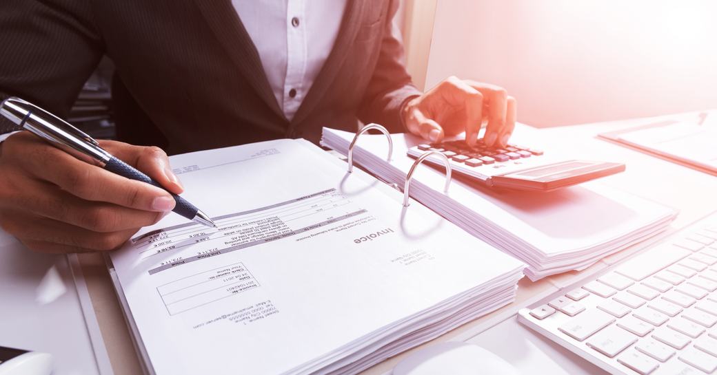 Close-up Of A Businessperson's Hand Calculating Bill With Calculator