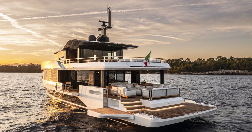 A96 by Arcadia Yachts shown at sunset, on anchor in still waters with land in background. Image of aft deck with all side wings open to extend the aft deck area