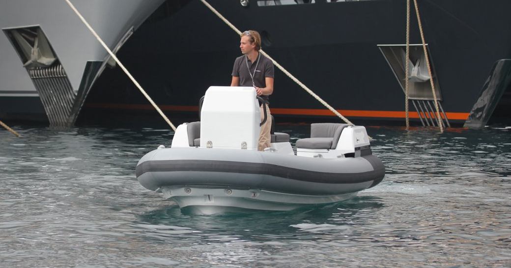 Man on small RIB in front of yachts