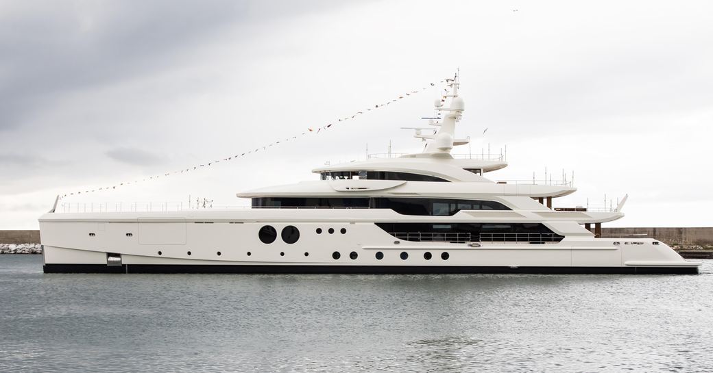 Benetti superyacht KASPER 7 when first launched showing the flags flying from bow to top of radar mast, grey day and the yacht is shown port side profile in still waters