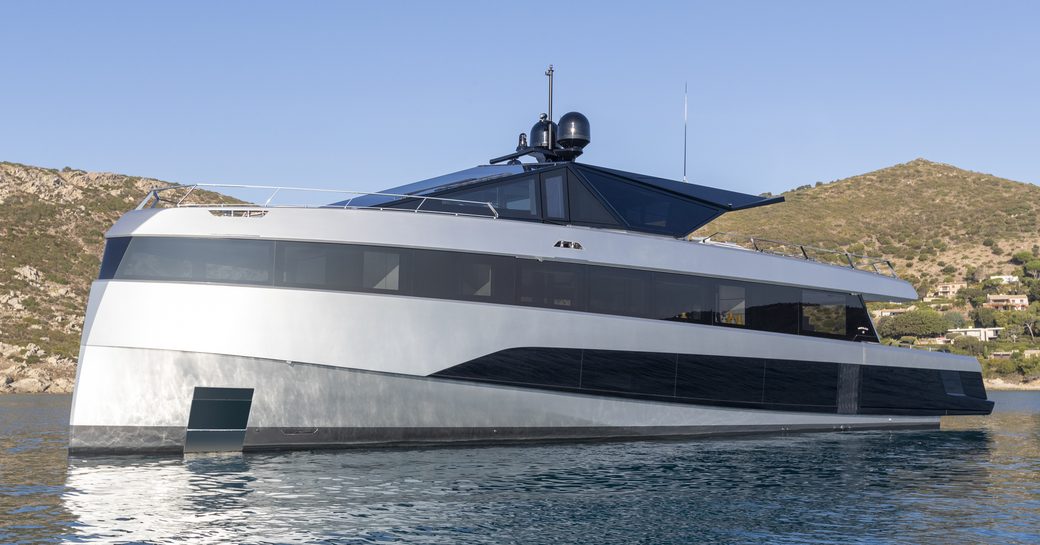 Wally wallywhy200 shown from water level looking towards port bow and side profile. yacht is stationary in calm waters with land in background on calm day