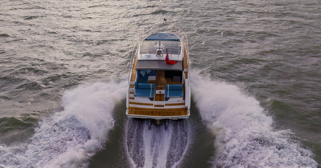 Fairline Targa 40 shown in running shot from the stern, sunset with land in background