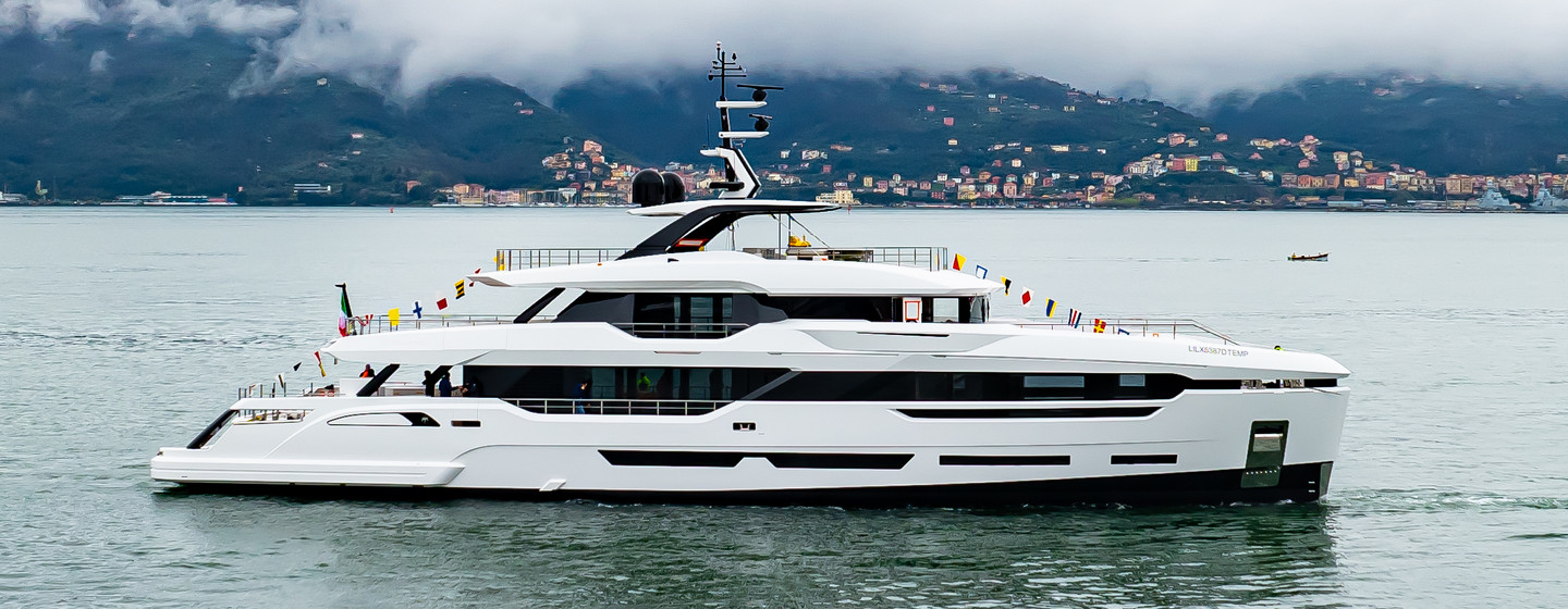 Baglietto yacht ASTERA starboard side profile underway at launch, flags on display