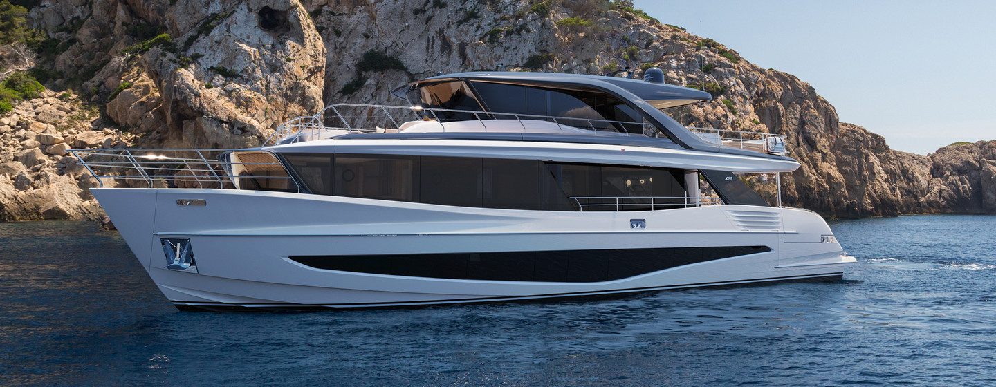 Princess Yachts X90 at anchor in front of a rocky backdrop