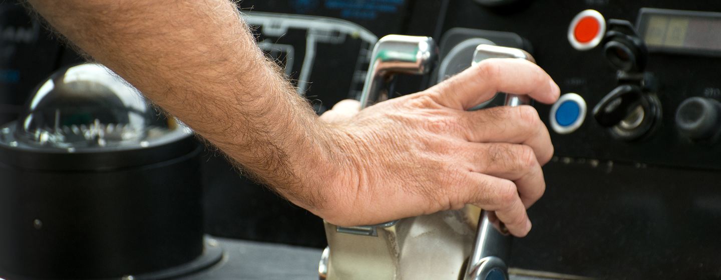 Captain's hand on ship throttle.