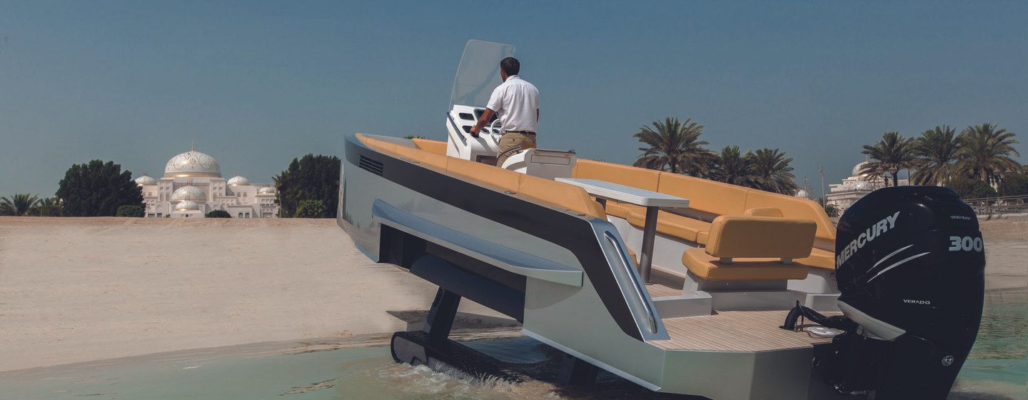 Amphibious tender moving from water to beach with man at helm