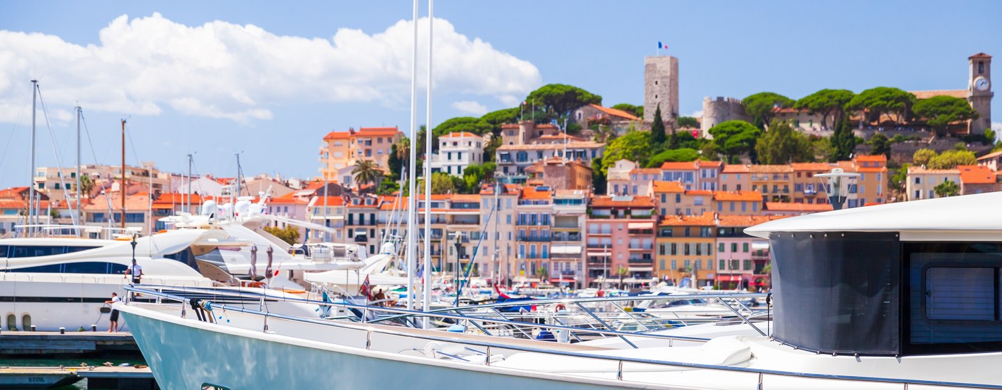 Water level view of Cannes marina with view of Old Town in background. Motor yachts moored in the foreground.