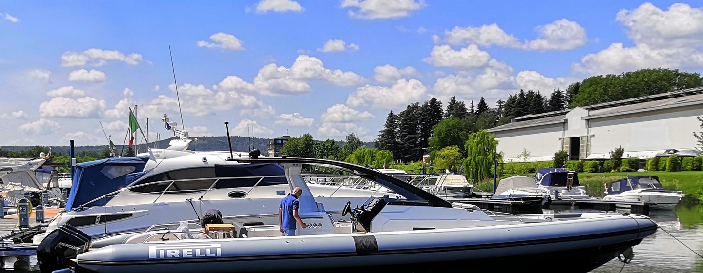 Side view of Tecnorib Pirelli 42 inflatable boat at dock in marina, surrounded by forests and large buildings.