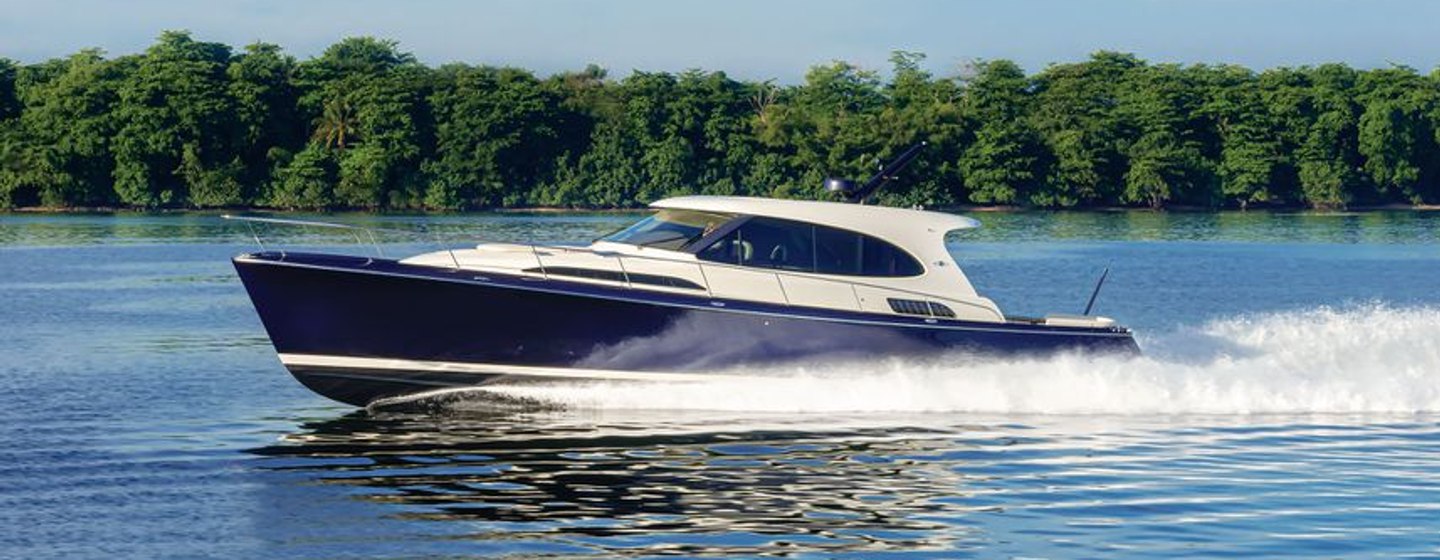 Side view of Palm Beach GT60 underway, surrounded by sea and dense foliage in background.