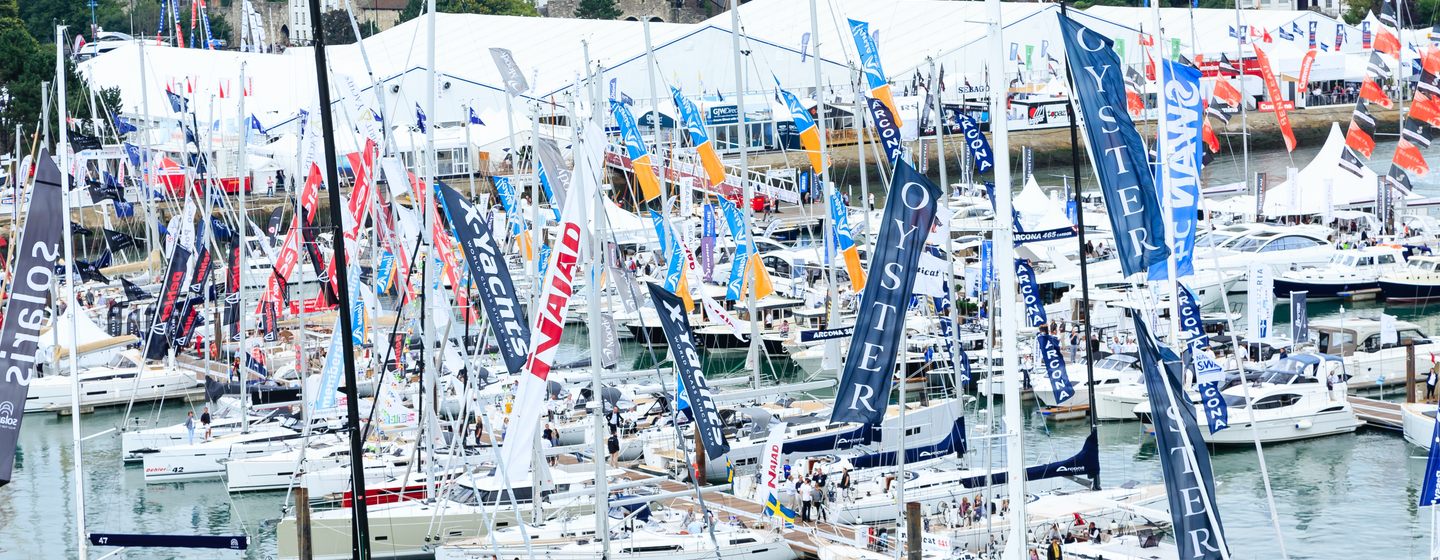 Overview of SIBS, many sailing boats and motor yachts anchored at berths, with exhibition tent in background