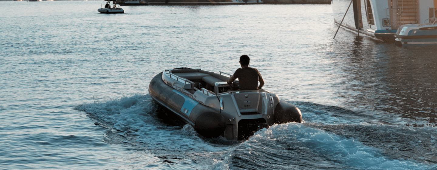 Avon eJet 450 tender view from behind being driven with a swell of water and a large yacht in the background