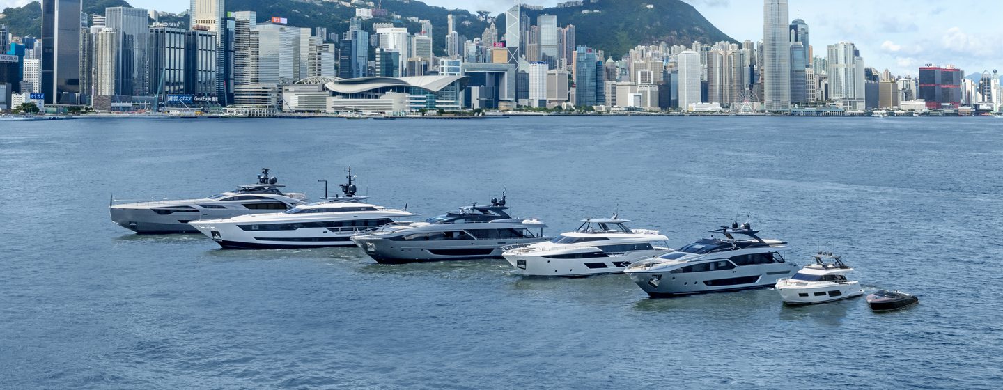 Ferretti Group fleet underway, surrounded by sea and cityscape in background