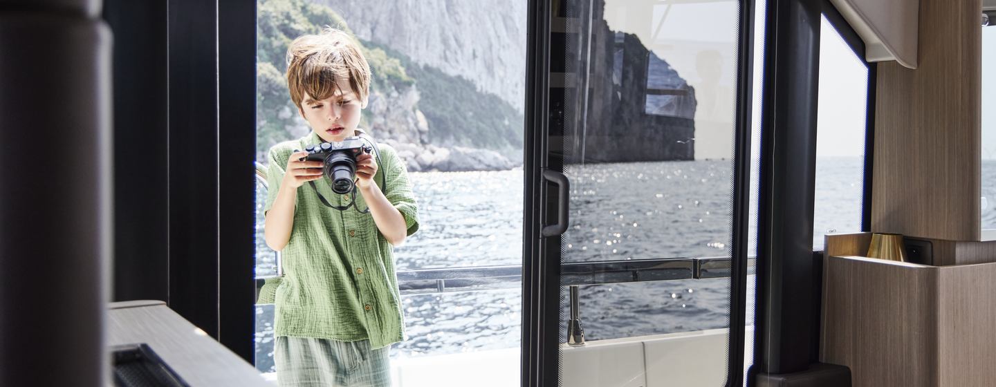 Prestige Yacht F4.9 for sale at Southampton Boat Show, image shows little boy playing with camera on the side deck, shot taken from interior