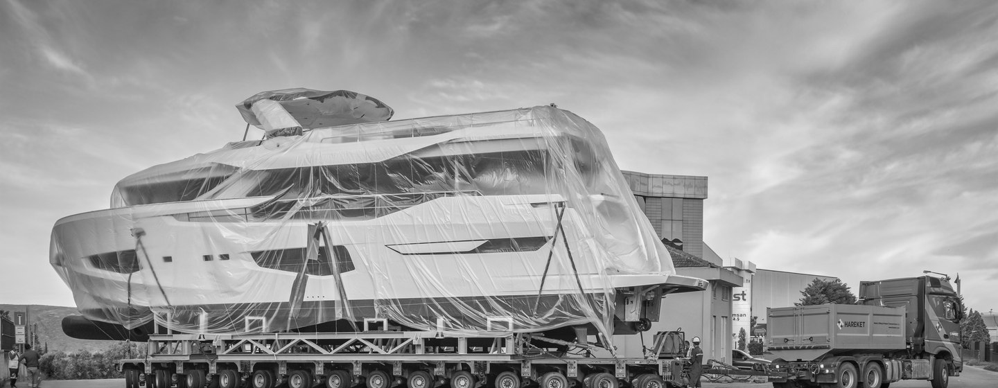 Side view of Numarine 26XP in transit on trailer through shipyard facility