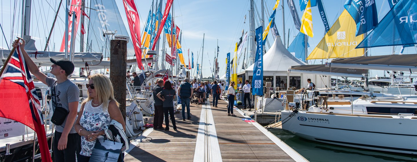 A pontoon at Southampton Boat Show, with visitors walking along looking at moored yachts on either side.