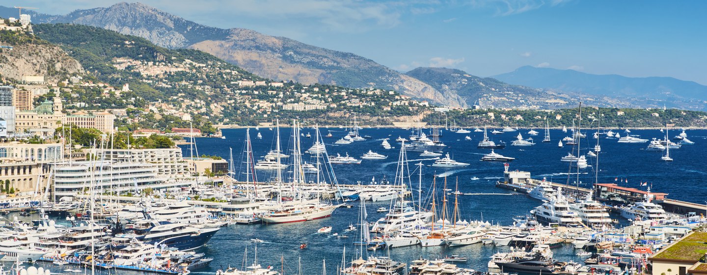 Elevated view over the Monaco Yacht Show at Port Hercule, many motor yachts at anchor on slips plus many sailing boats at sea